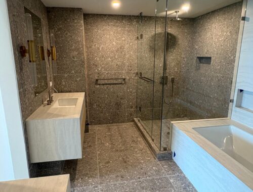 luxury-bathroom-remodeling-featuring-floor-to-ceiling-grey-stone-tiles-a-glass-enclosed-walk-in-shower-and-modern-vanity-completed-by-a-general-contractor-miami-fl