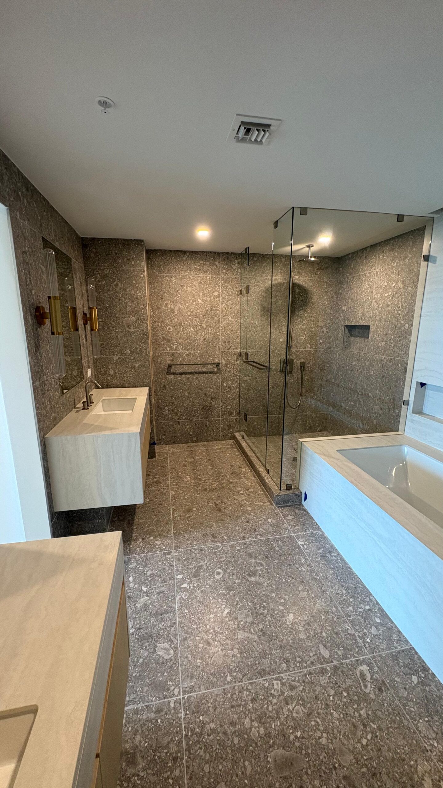luxury-bathroom-remodeling-featuring-floor-to-ceiling-grey-stone-tiles-a-glass-enclosed-walk-in-shower-and-modern-vanity-completed-by-a-general-contractor-miami-fl